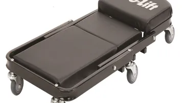 Black folding Z creeper with padded cushions, steel frame and six swivel casters on a garage floor