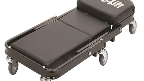 Black folding Z creeper with padded cushions, steel frame and six swivel casters on a garage floor