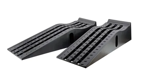 Pair of black molded plastic car service ramps with grooved tire channels on a garage floor