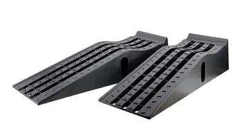 Pair of black molded plastic car service ramps with grooved tire channels on a garage floor