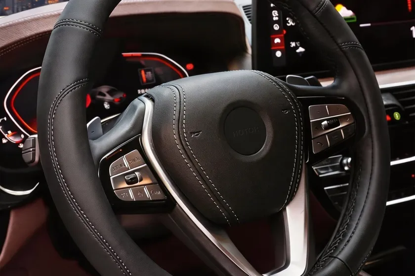 HOTOR black leather steering wheel cover with stitched seam shown on a round car steering wheel