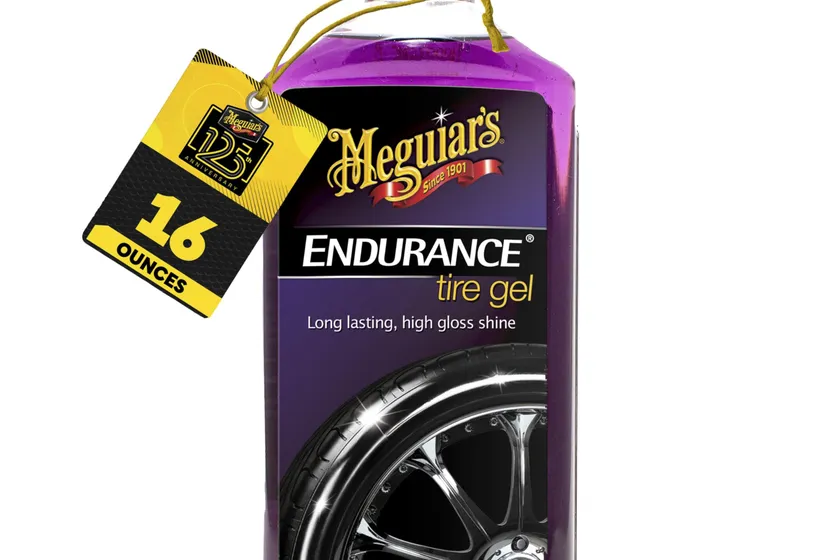 Meguiar's Endurance Tire Gel black squeeze bottle standing in front of a glossy car tire