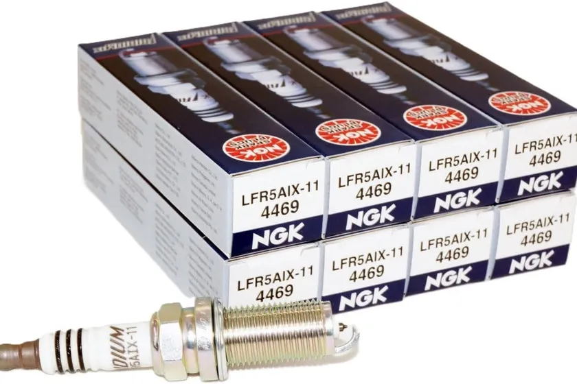 Eight NGK LFR5AIX-11 Iridium IX spark plugs arranged in two rows next to a stack of NGK boxes